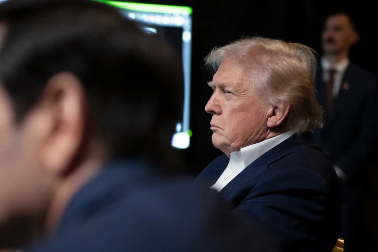The side profile of Donald Trump, frowning and listening