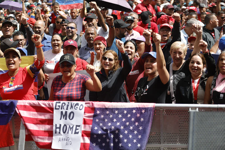 A crowd during a protest, some carrying a sign that says 'GRINGO GO HOME.'