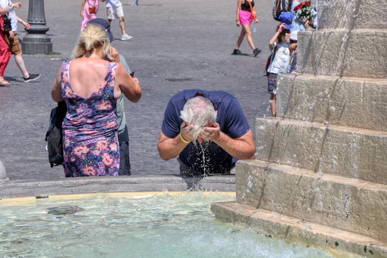 Hombre con el pelo blanco refrescándose en una fuente