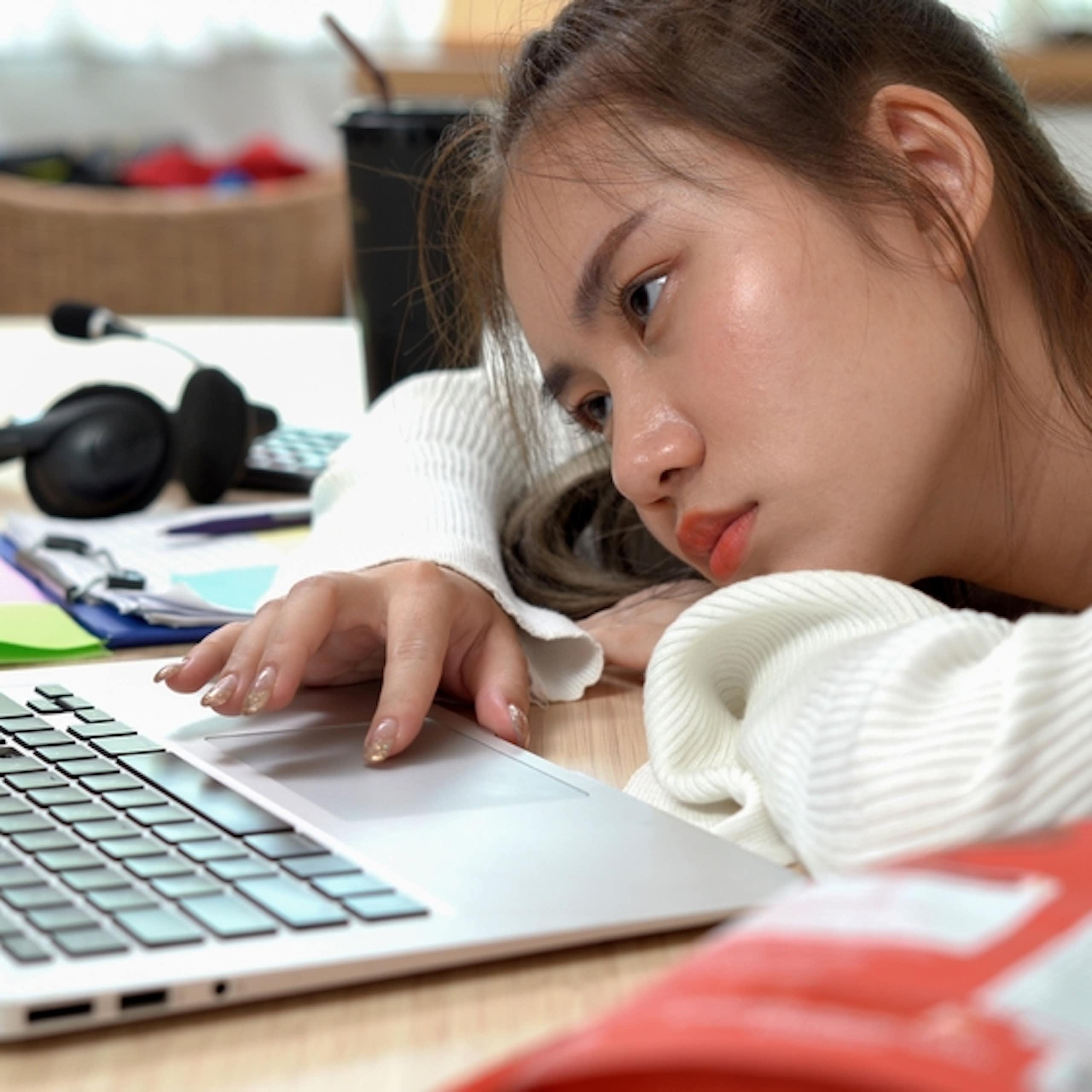 Une jeune femme qui travaille sur son ordinateur en s'ennuyant.