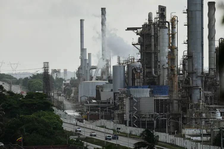 An oil refinery with smoke rising from smoke stacks.