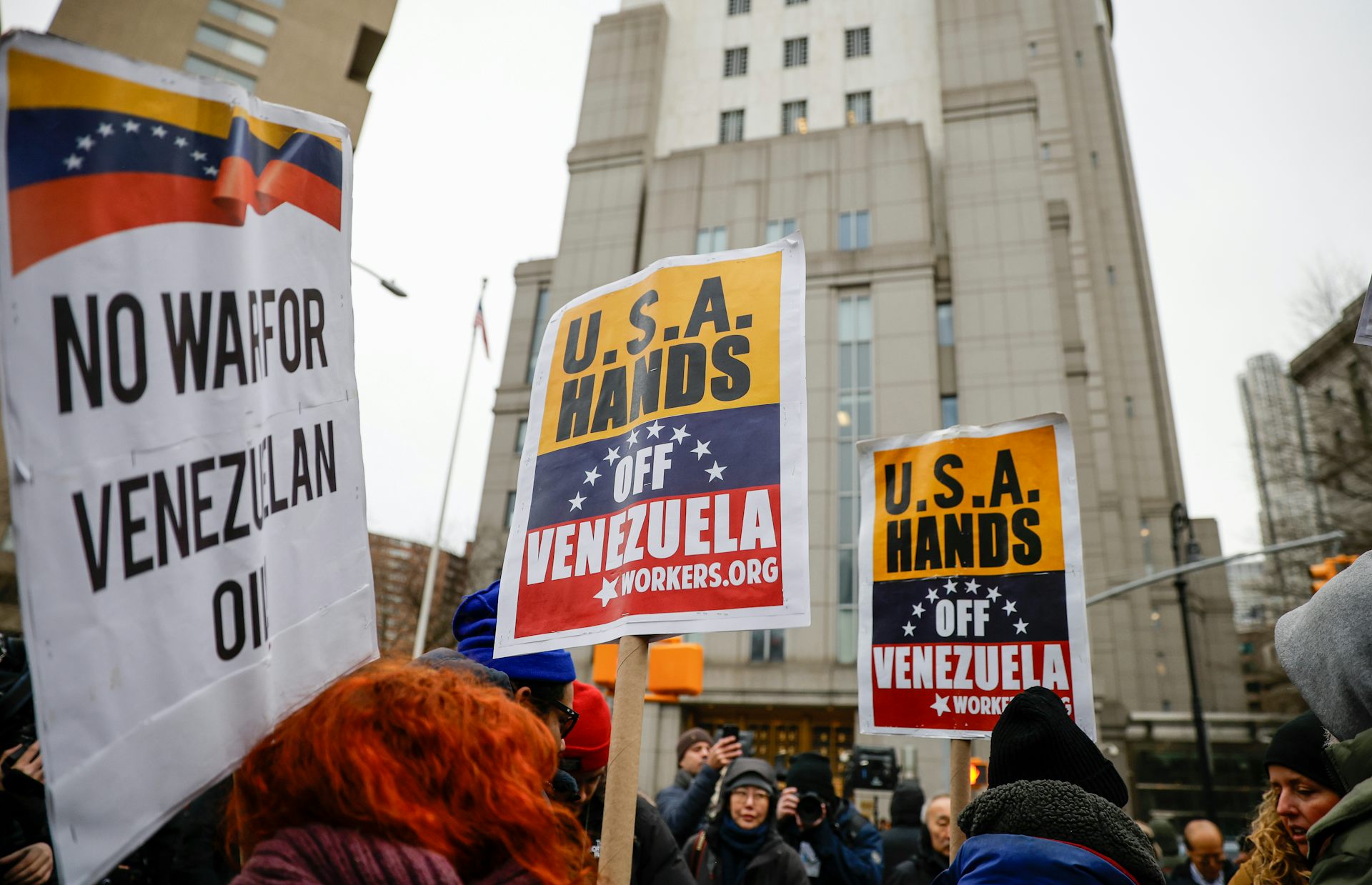Los manifestantes frente al tribunal portan carteles que dicen No a la guerra contra el petróleo venezolano y Manos fuera de Venezuela.