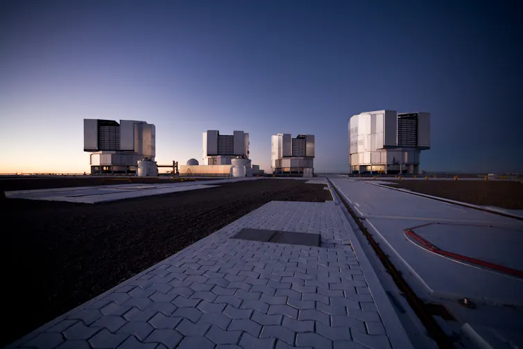 Quatro unidades de telescópio em uma plataforma de concreto.