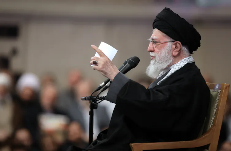 A man in traditional Iranian garb speaks.
