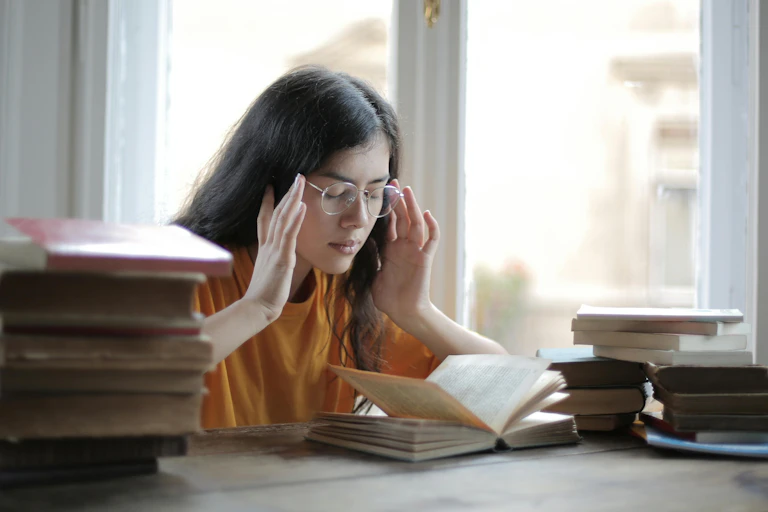 Young woman with closed eyes touches her temples and jaws.