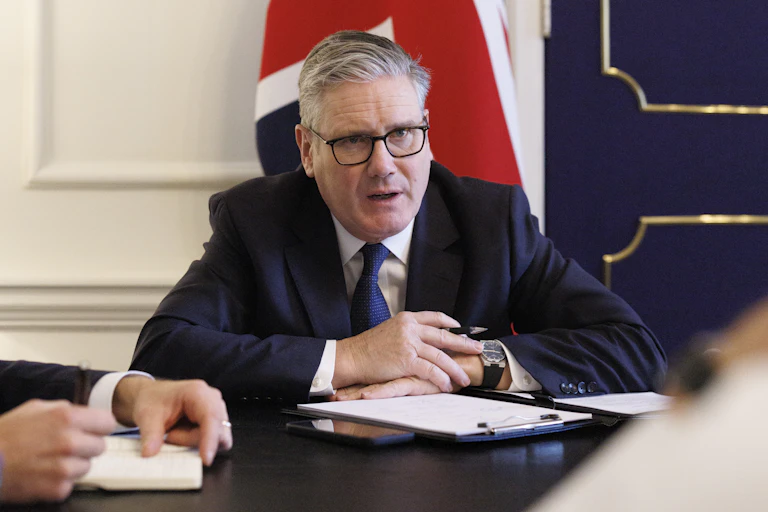 Keir Starmer sitting at a desk talking to colleagues.