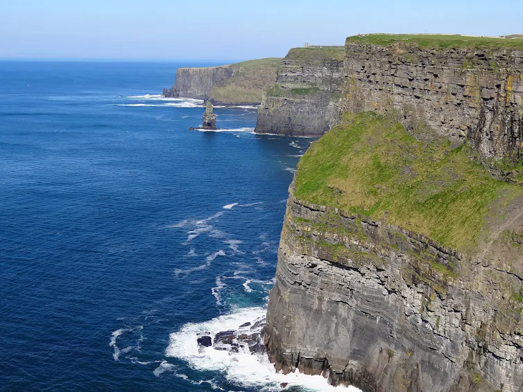Huge cliffs overlooking a very blue sea.