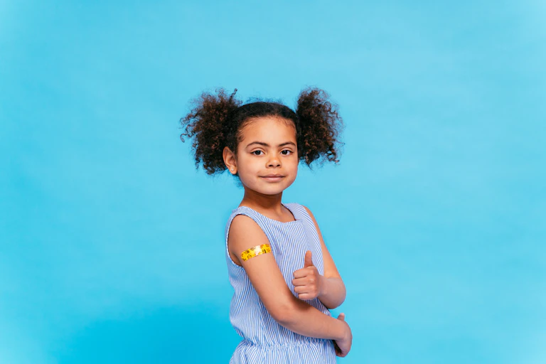 Child with plaster on upper arm giving the thumbs up.