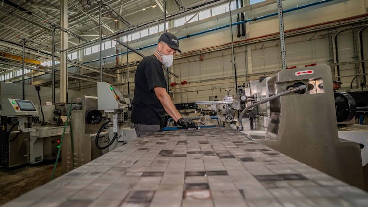 A worker wearing a mask handles magnets.