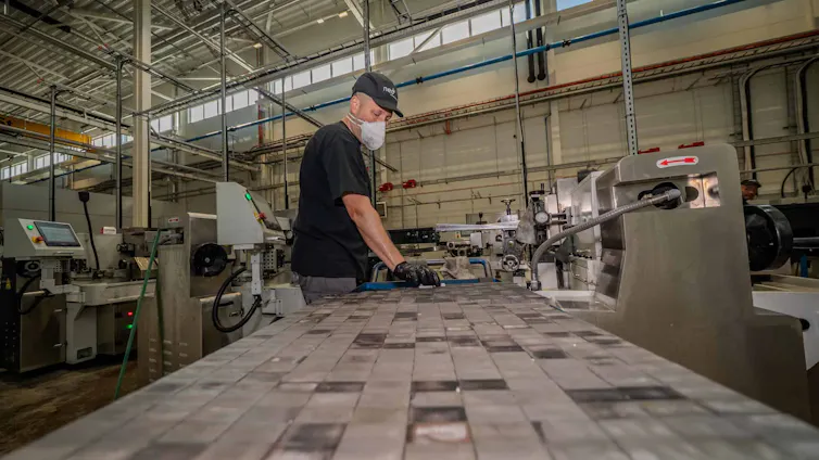 A worker wearing a mask handles magnets.
