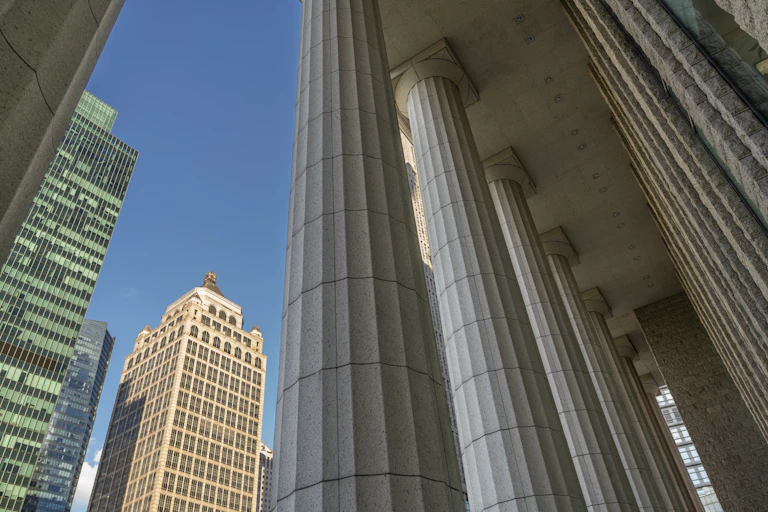 A low-angle view of skyscrapers juxtaposed with classical columns