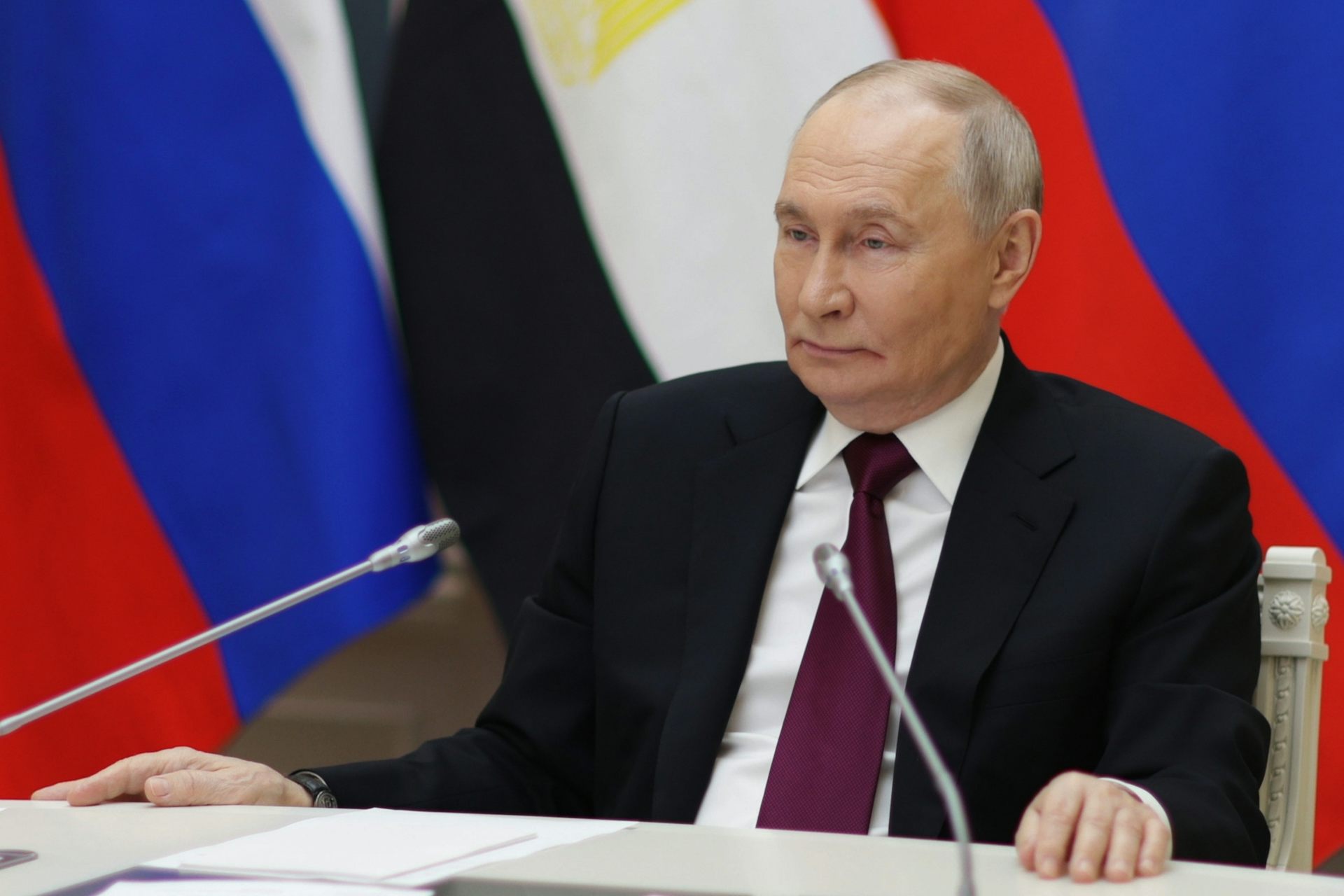 Le président russe Vladimir Poutine assis à son bureau devant un micro
