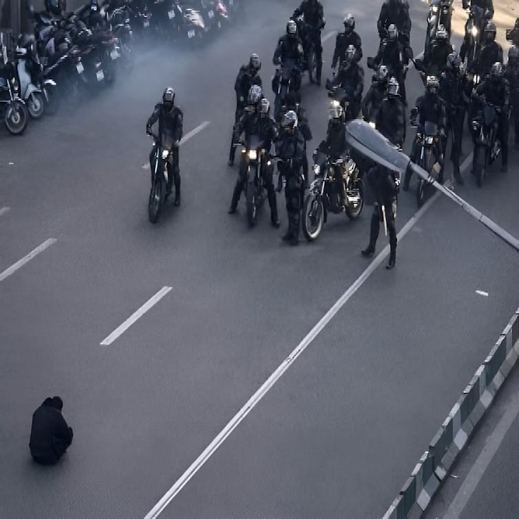 Iranian security forces confront a lone protester during demonstrations.