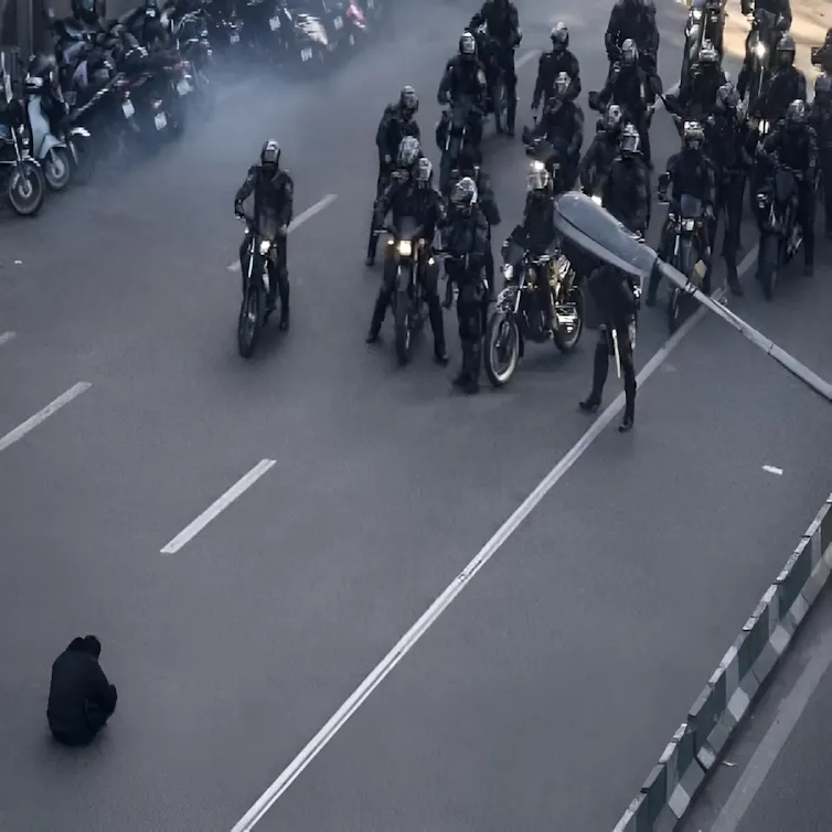 Iranian security forces confront a lone protester during demonstrations.