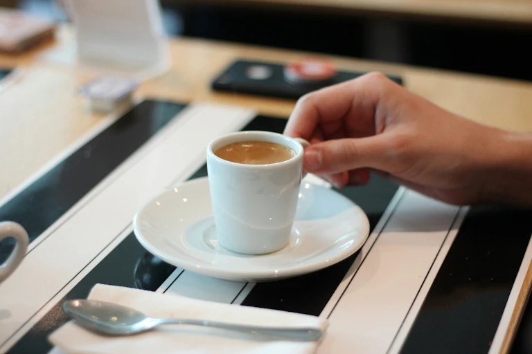 A hand holds an espresso coffee.