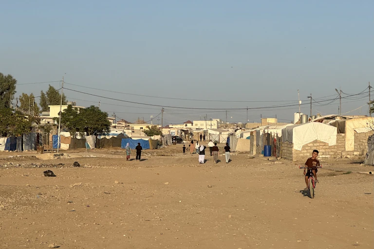 A landscape view of a refugee camp showing tents and people going about their business.