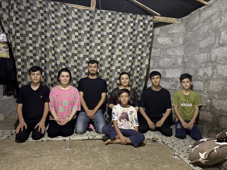 A family sit on the floor and pose for a picture