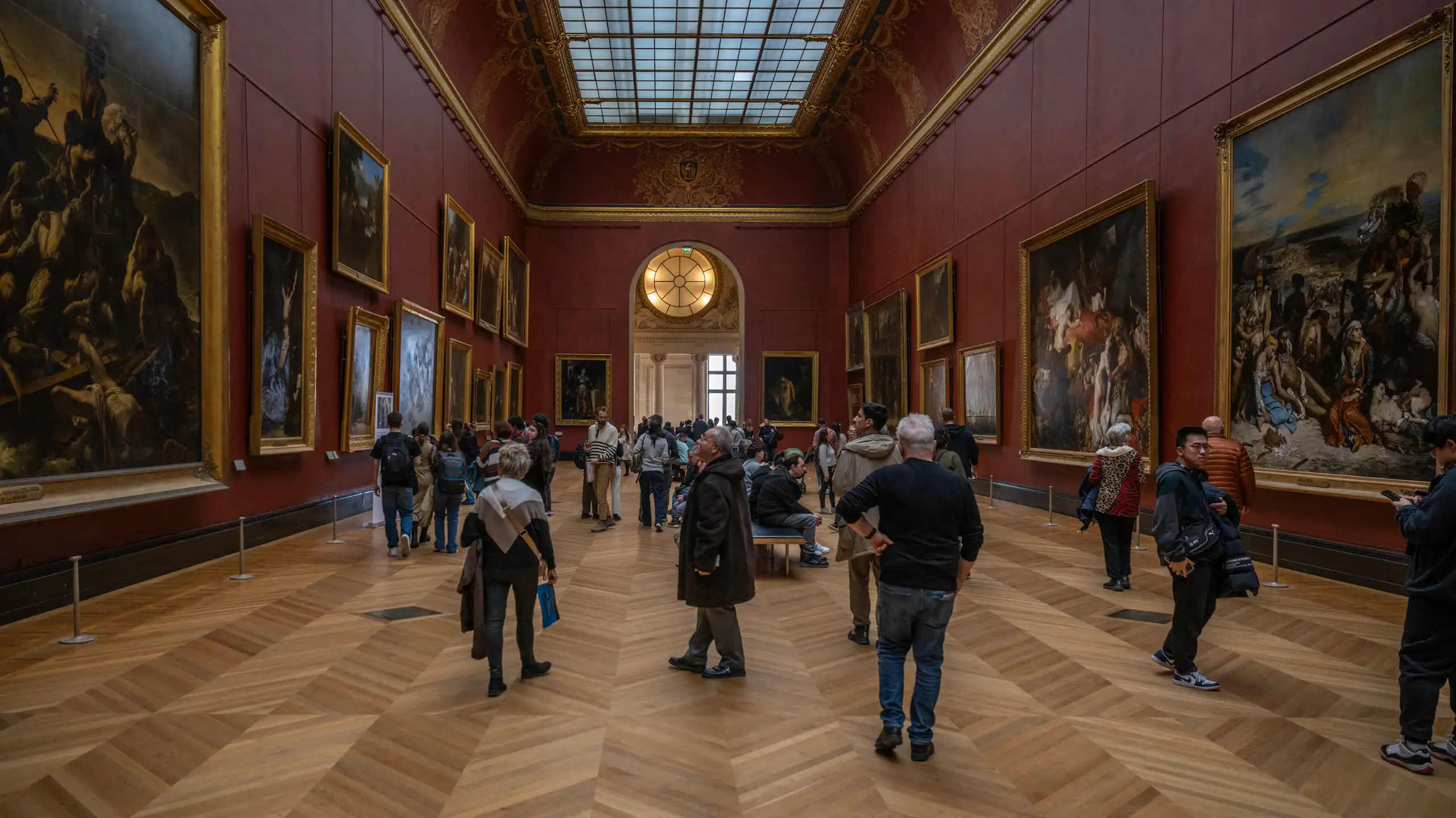 Des visiteurs devant des tableaux dans une des salle du Louvre.