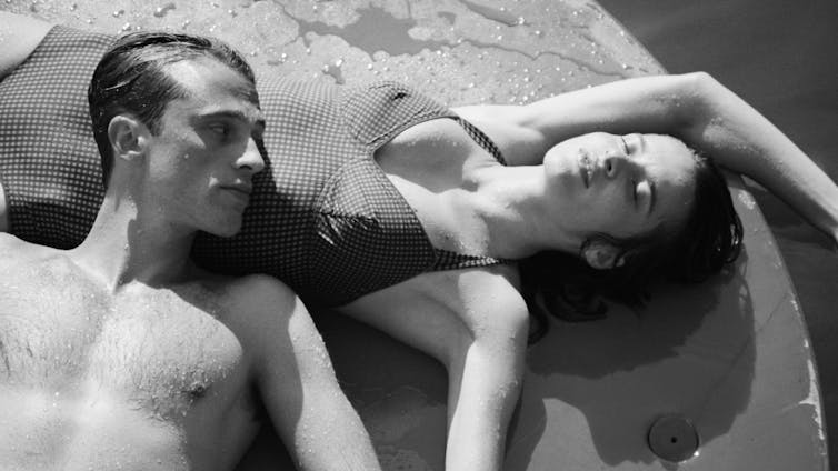 Un hombre joven y una mujer tumbados en un entorno veraniego con bañadores.