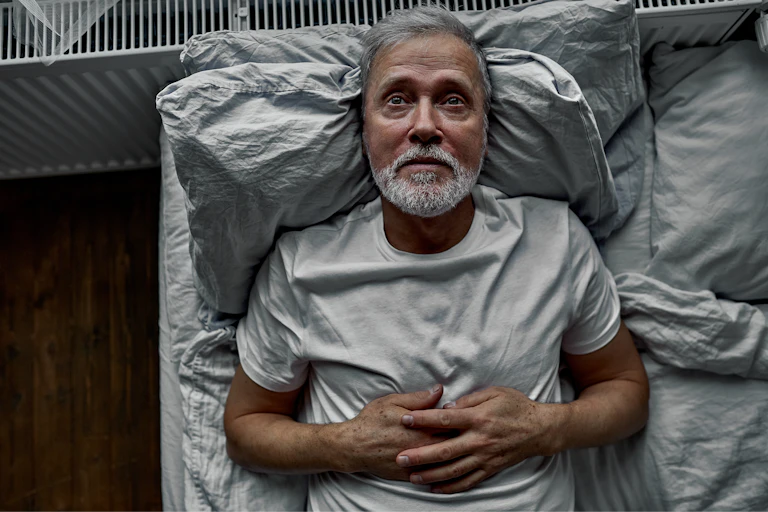 Head and shoulders shot of man lying awake in bed at night