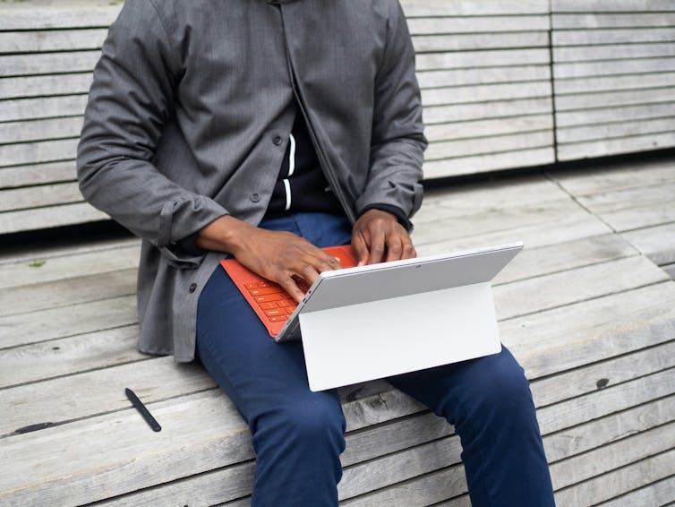 A person typing outdoors on a keyboard.