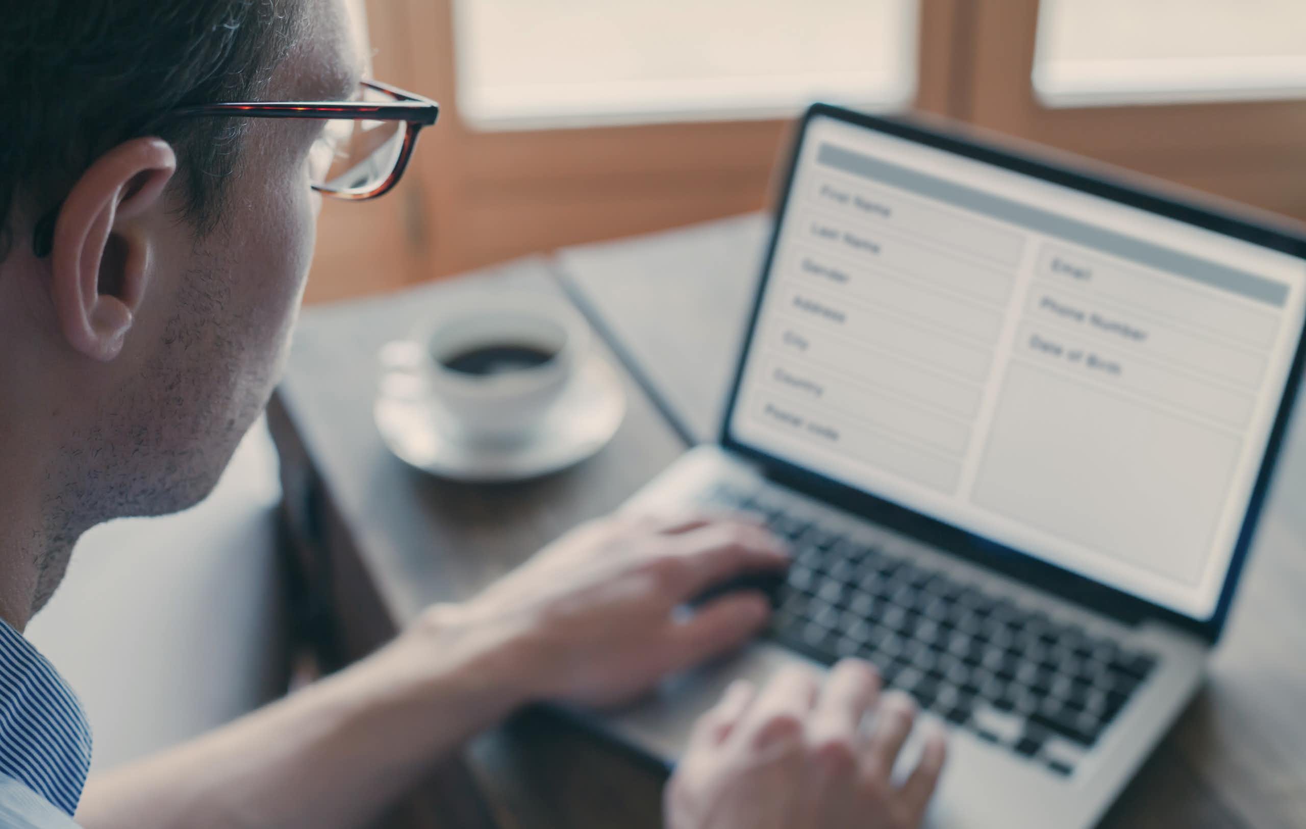 Un home amb ulleres mira la pantalla d'un ordinador portàtil que mostra un formulari.