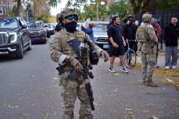 A soldier holds a rifle on a city street.