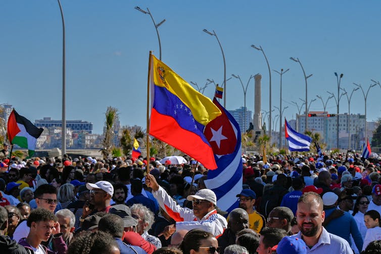 A crowd hold aloft flags.