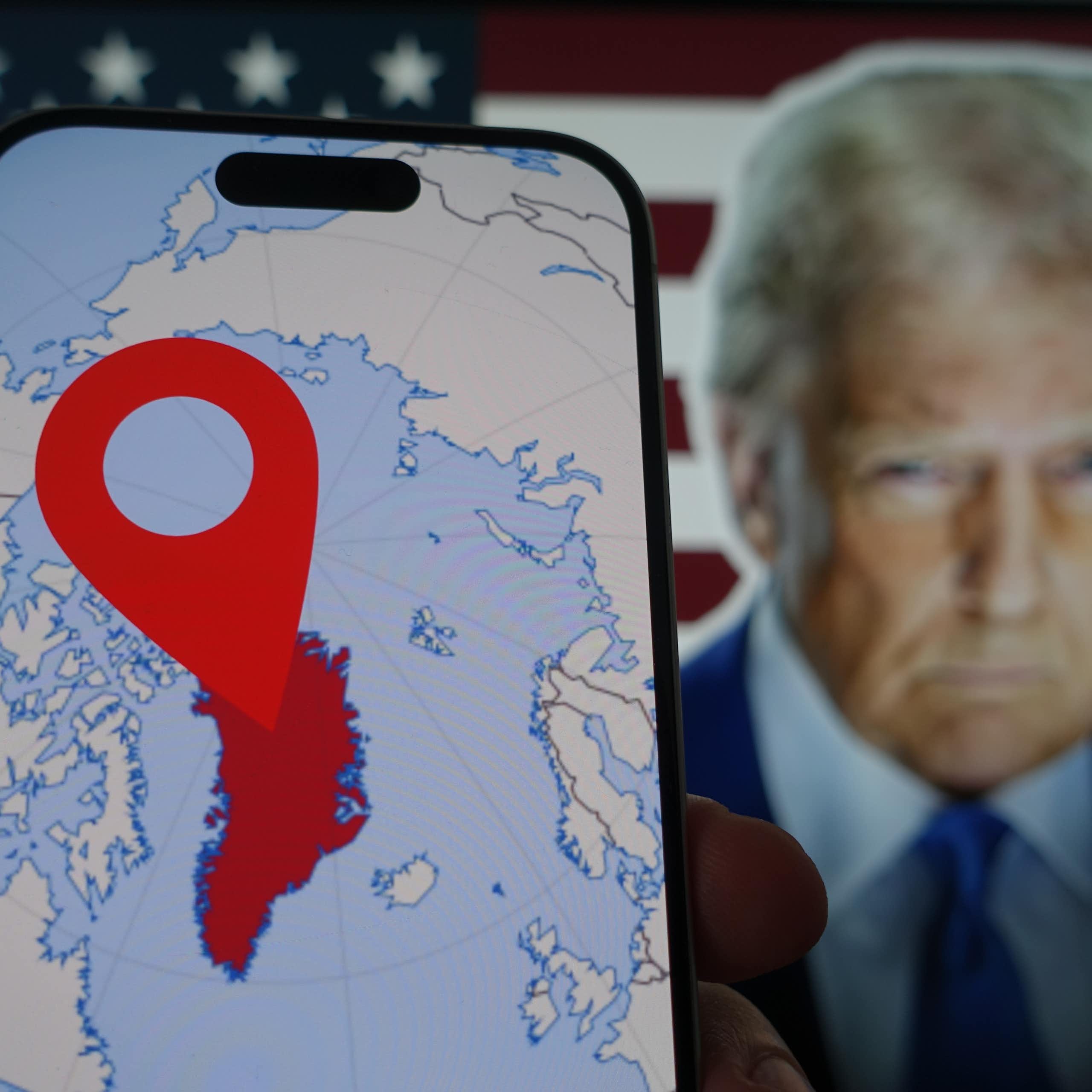 A phone showing a map of Greenland and a picture of Donald Trump in the background.