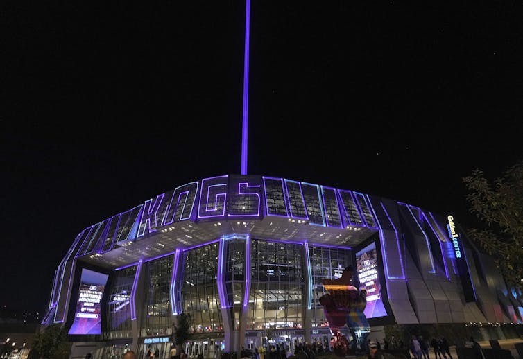 A building at night is lit up with purple lights that read