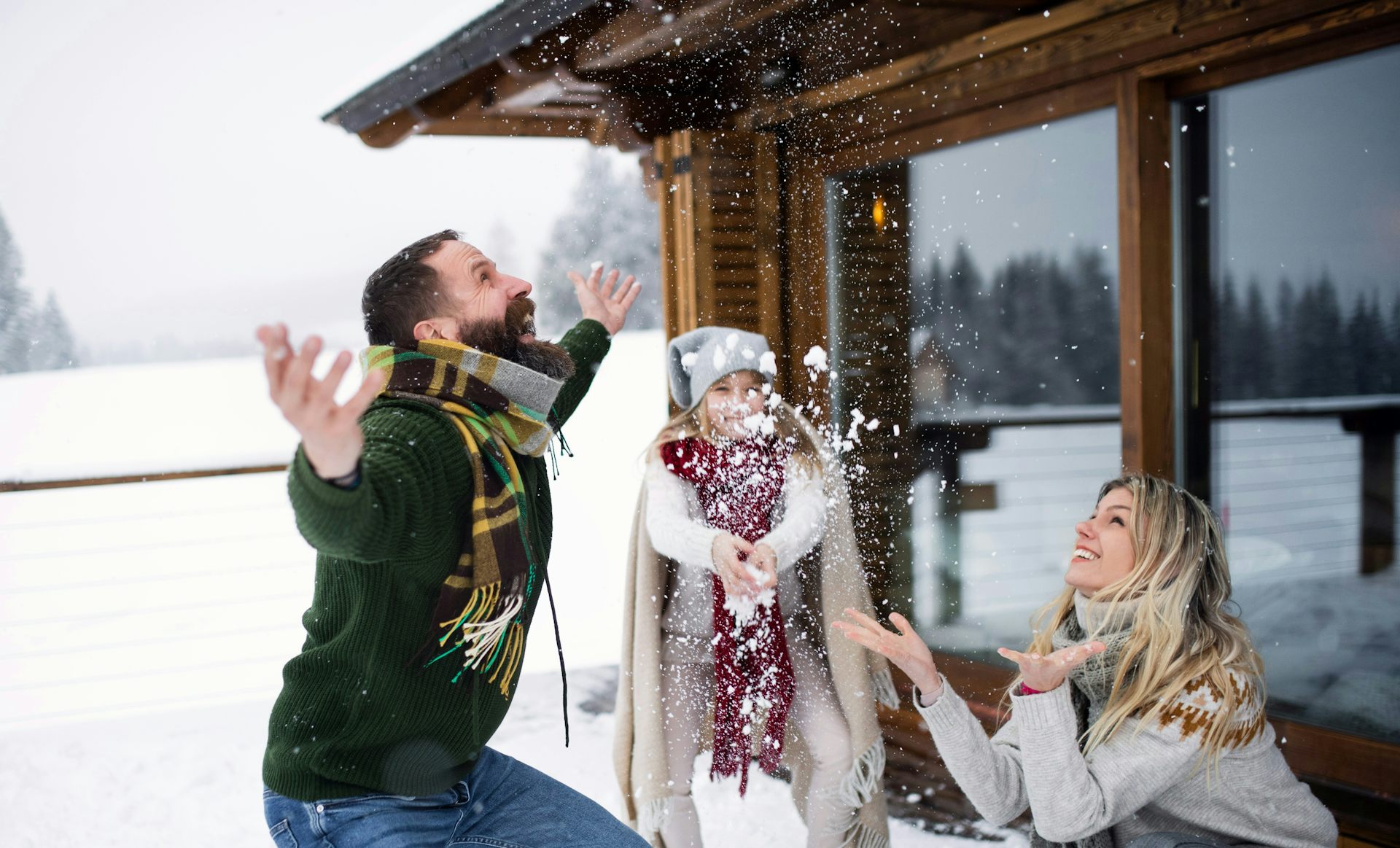 A family of three is outdoors enjoying the snow.