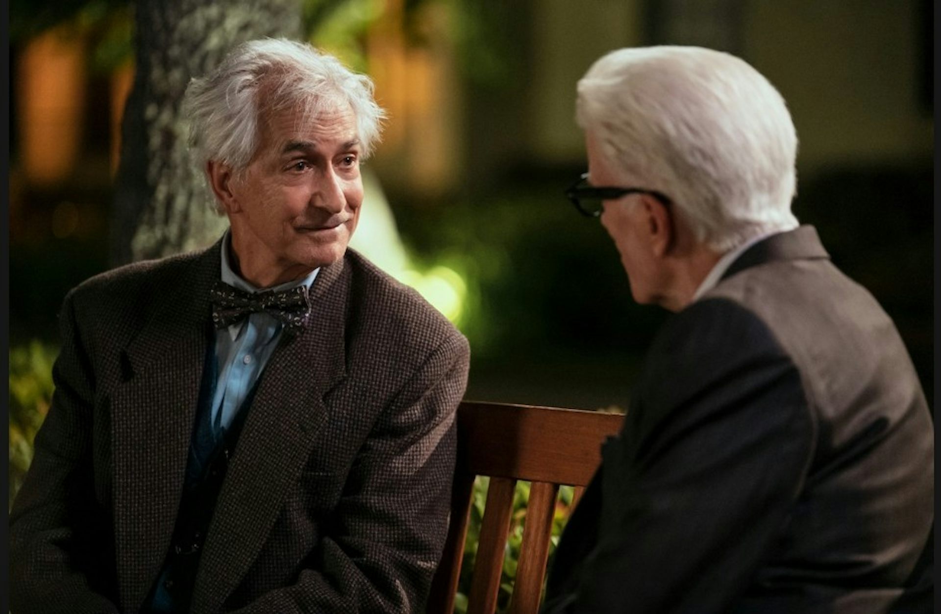 Two men in discussion on a bench.