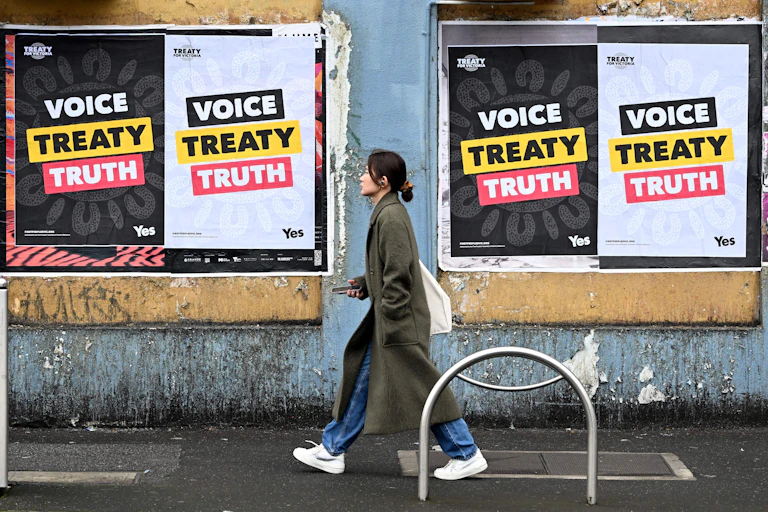 A woman walking past large signs that say voice, treaty, truth