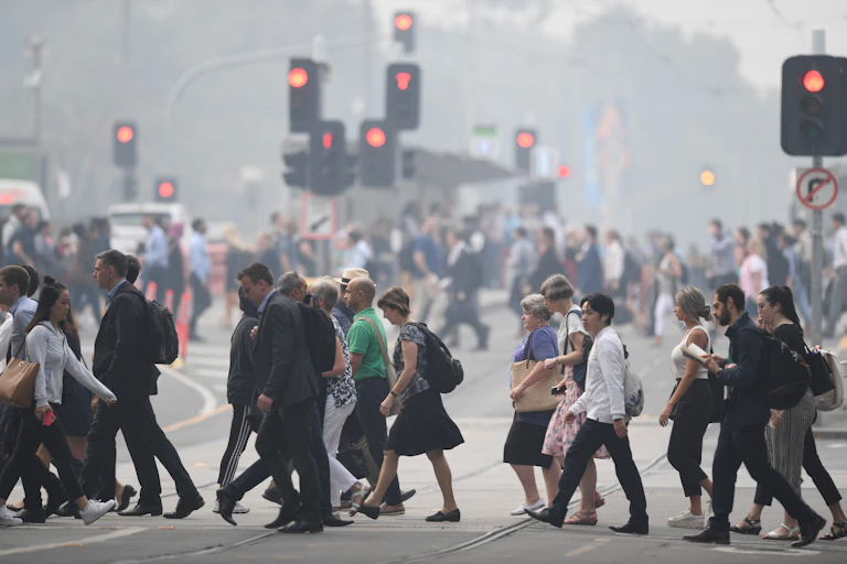 Office workers cross at traffic lights in hazy city.