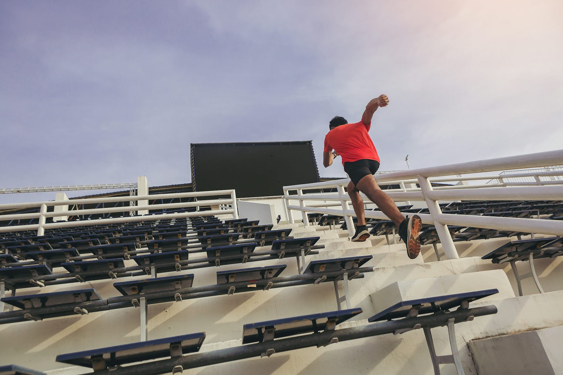 A man sprints up some stairs at a sports stadium.