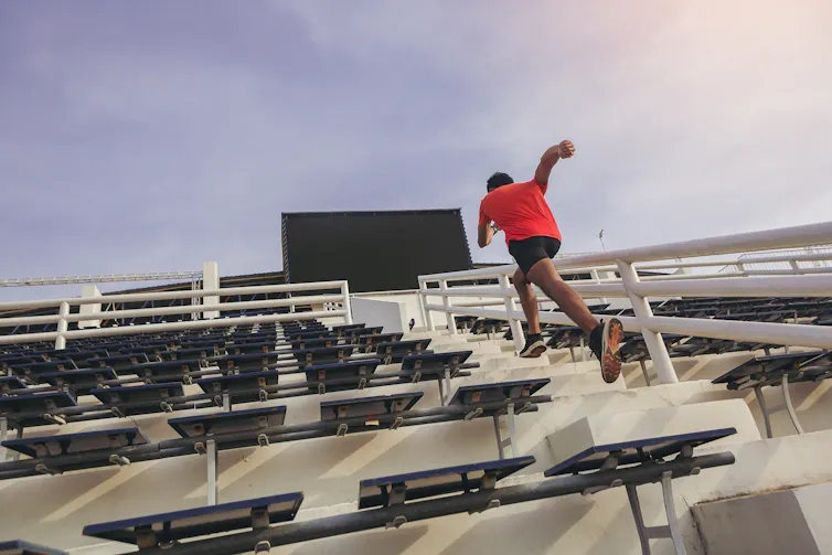A man sprints up some stairs at a sports stadium.