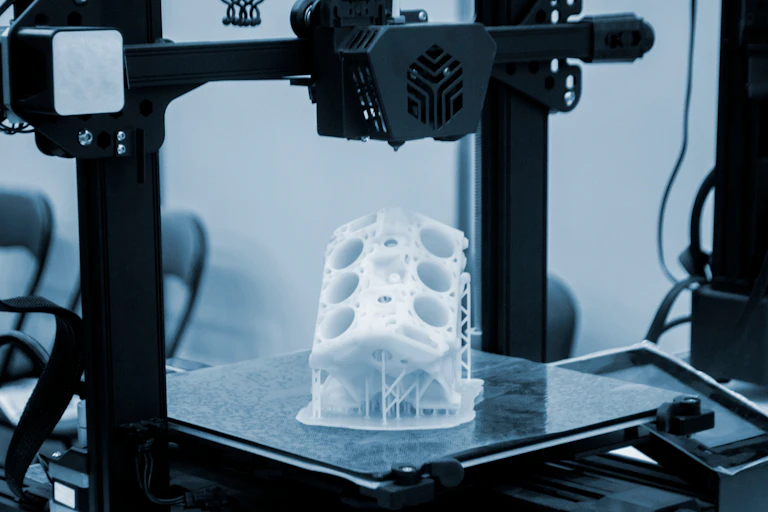 Prototype de moteur de voiture imprimé sur une imprimante 3D à partir de plastique blanc fondu sur une imprimante 3D en surface de travail.
