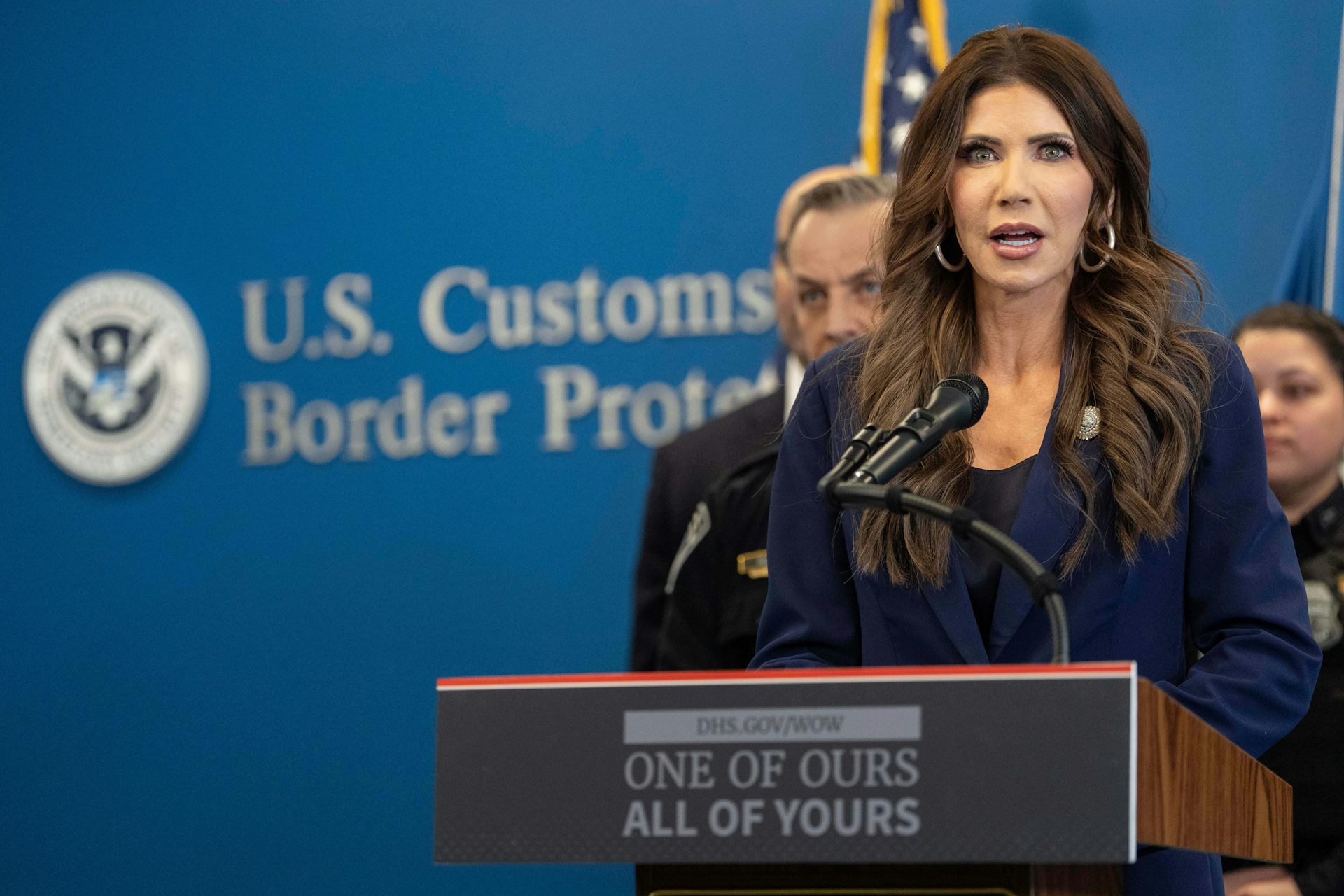 Kristi Noem, the Homeland Security secretary, stands behind a podium at a news conference.