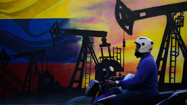 Una motocicleta pasa frente a un mural de temática petrolera.