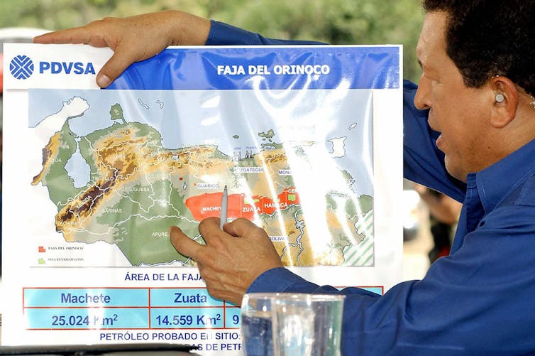 Un hombre sostiene un mapa detallado con el logo de PDVSA.