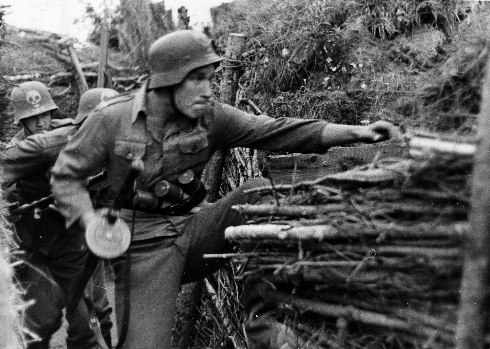 A man in an army helmet stands in a trench