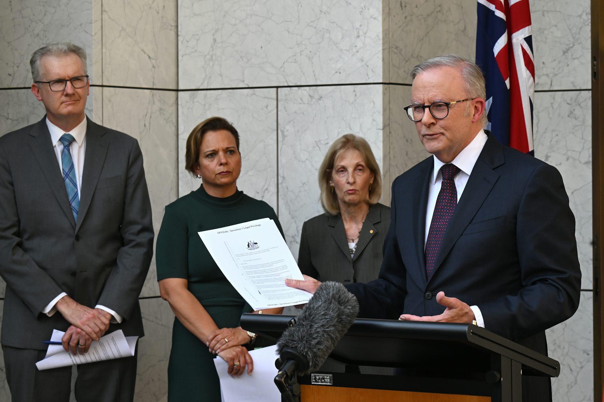 Anthony Albanese, right, speak at a lectern in front of other officials