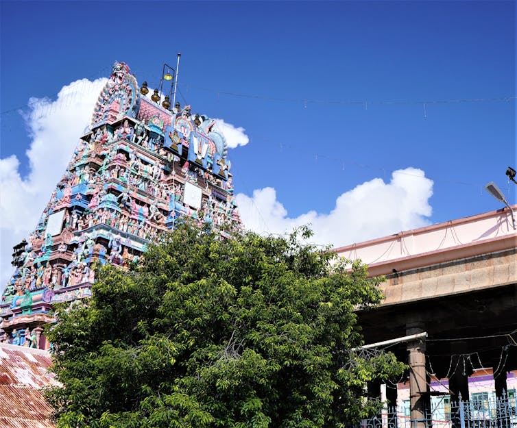 elaborate Hindu temply, blue sky, green tree in foreground