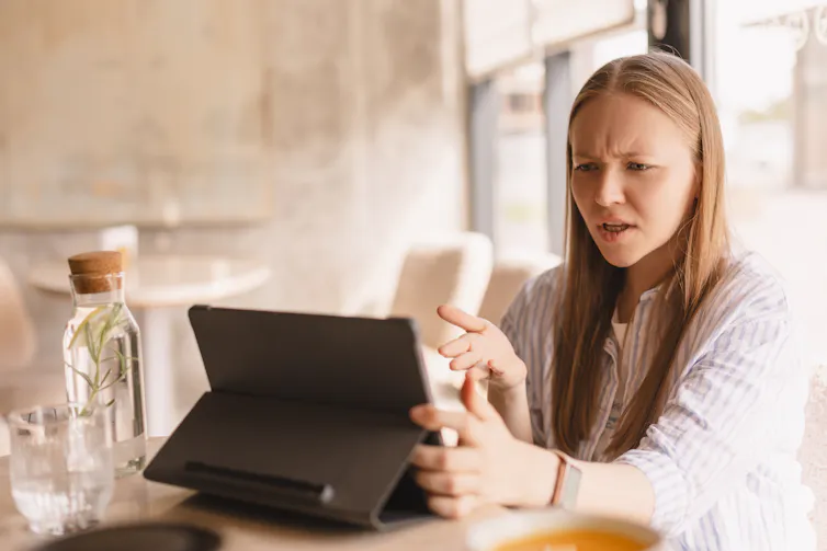 A woman angrily shouting at an ipad