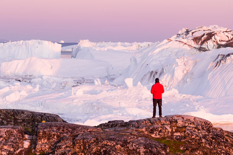 Man stands and looks at ice in Greenland