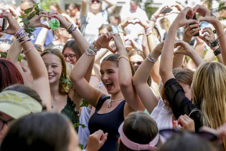 A group of young women make love symbols with their hands at a Taylor Swift concert.