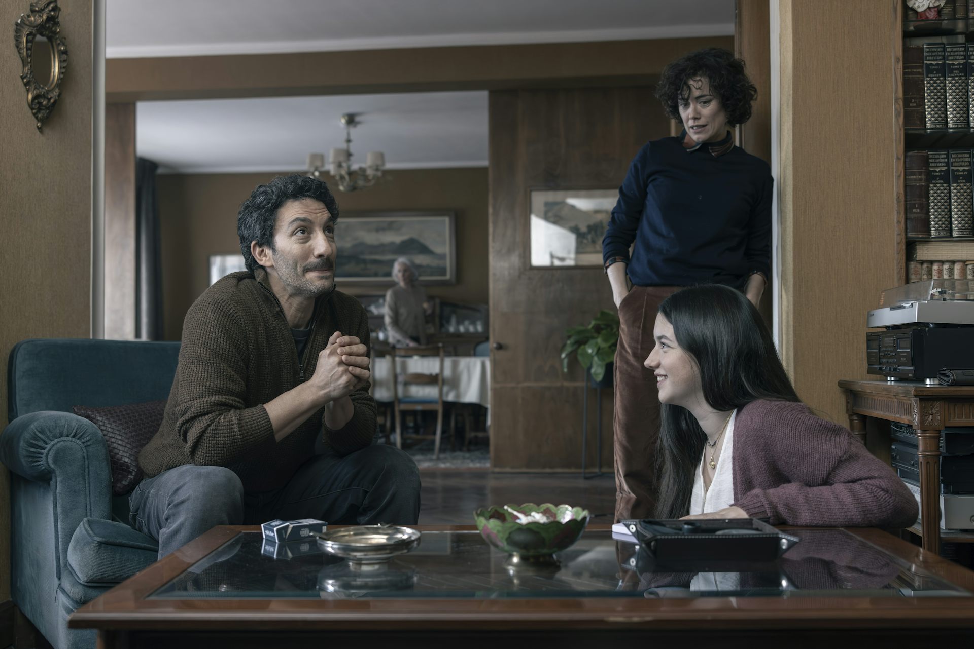 Una adolescente habla con un hombre mientras una mujer los observa.