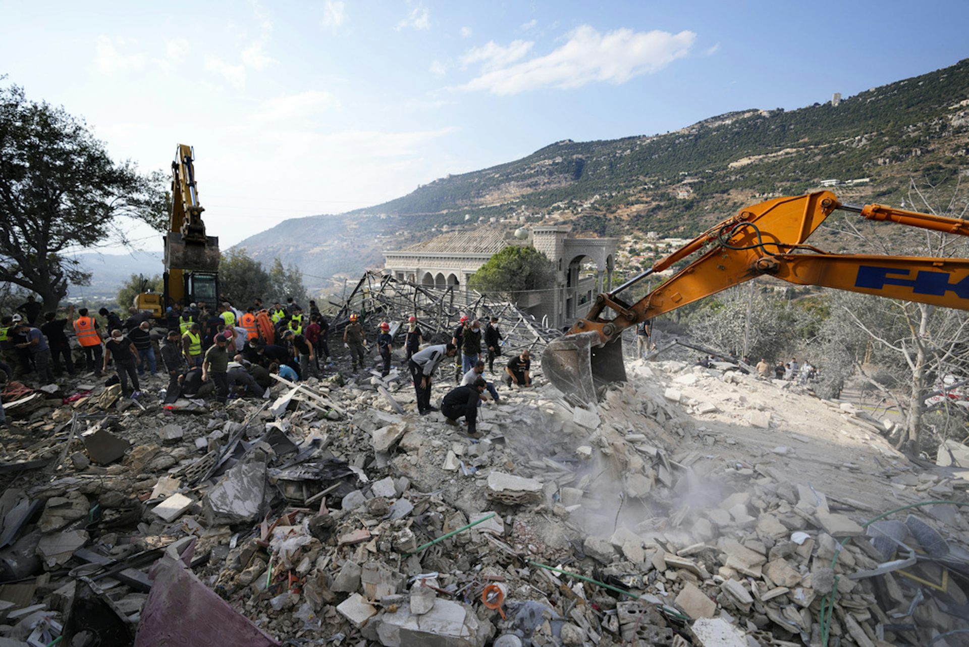 Rescue workers sift through a large pile of rubble.