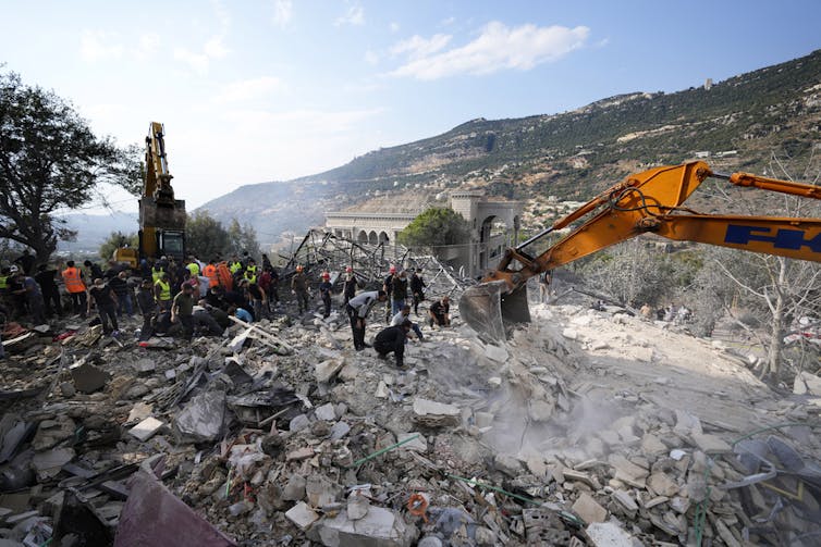 Rescue workers sift through a large pile of rubble.