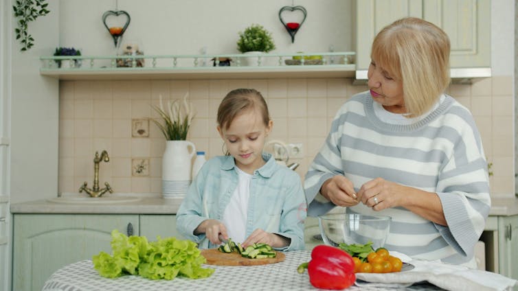 An older woman cooking with a young girl.